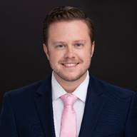 A person wearing a suit and tie smiling at the camera
Description automatically generated